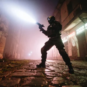 A soldier holding a new tactical flashlight, its powerful beam cutting through steam on a city street at night. The urban image has a cinematic, low-angle perspective.