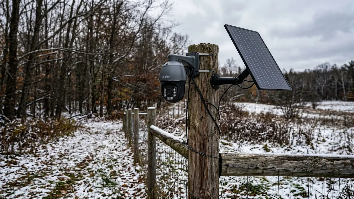 Solar powered pan-tilt CCTV camera mounted on fence post at rural Northern Michigan property edge in early winter
